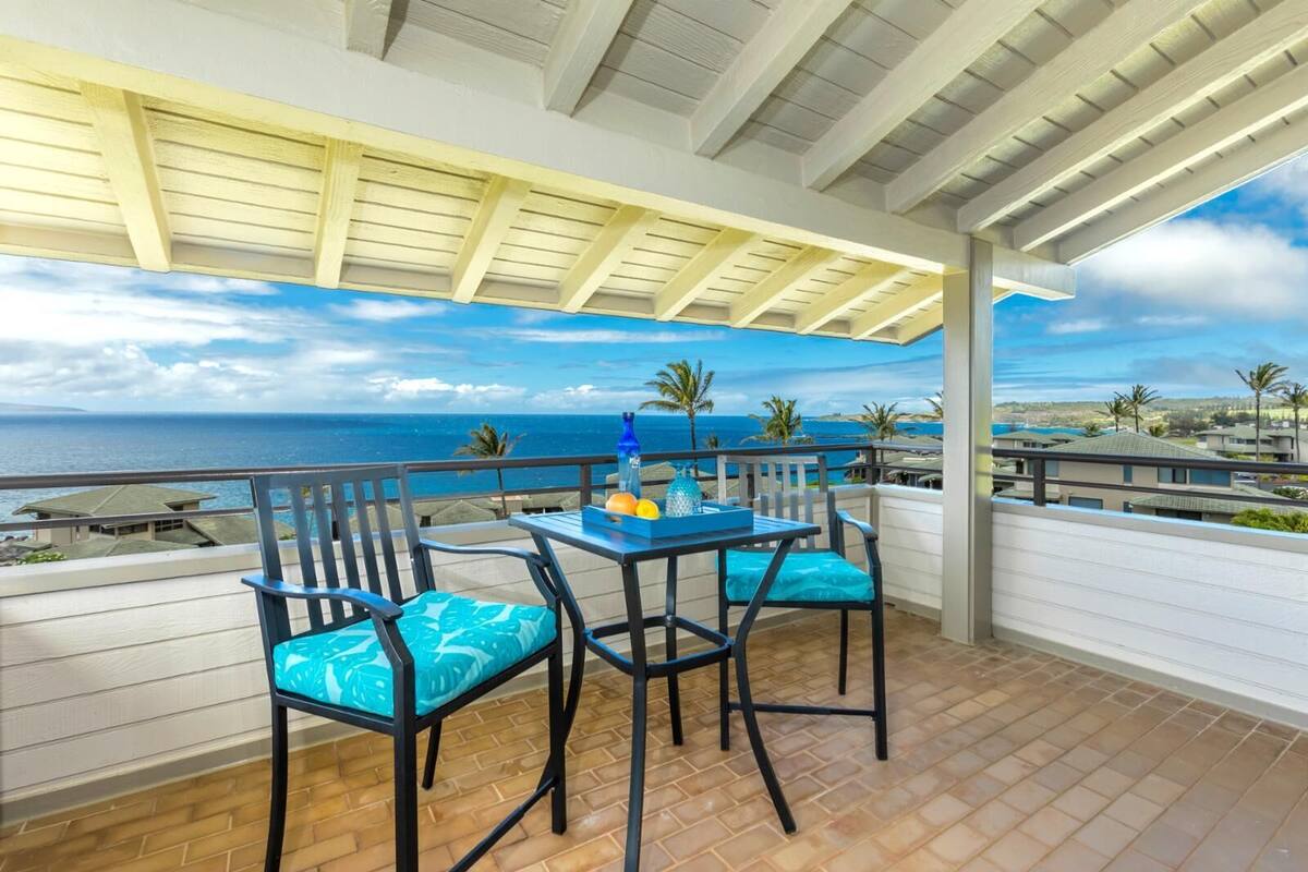 Uma área de estar coberta ao ar livre, com mesa e cadeiras, com vista para a costa.