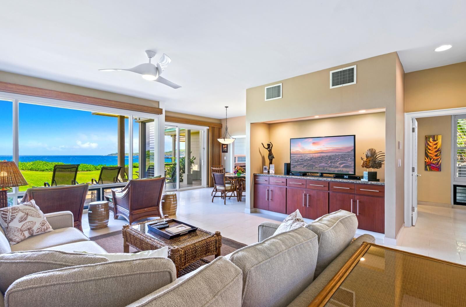 A spacious living area with a large TV, comfortable seating, and a view of the ocean.