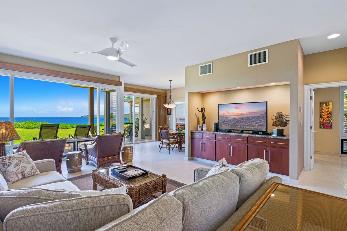 A spacious living area with a large TV, comfortable seating, and a view of the ocean.