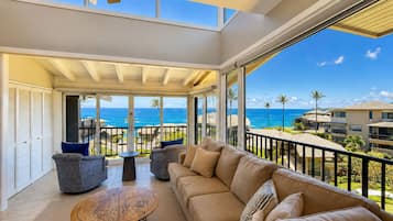 A spacious balcony with a view of the ocean, furnished with a sofa, chairs, and a coffee table.
