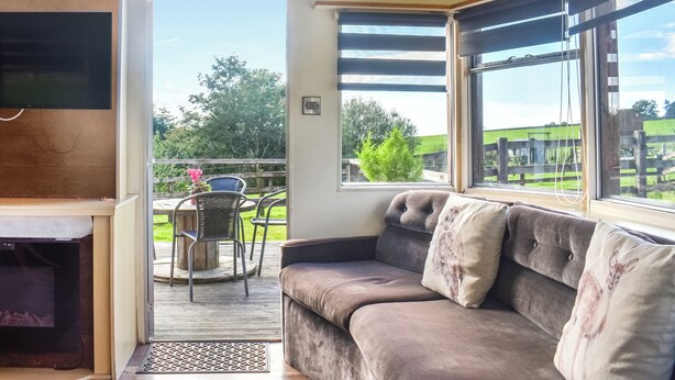 A cozy living area with a sofa and a television, a dining table with chairs, and a view of the outdoors.