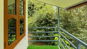 Ein Balkon mit künstlichem Grünrasen, Metallgeländern und Blick auf dichtes Grün.