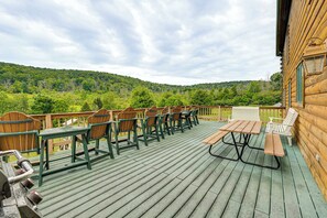 A wooden deck with outdoor seating and a view of a forested hill.