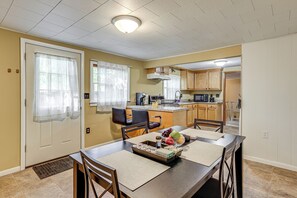 A dining area with a table set for four, a kitchen in the background, and a door with a window. - Accessible Home w/ Yard: 1 MI to Pere Marquette (Baldwin)