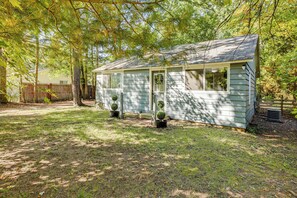A small, single-story cabin with a porch, surrounded by trees and a wooden fence. - Accessible Home w/ Yard: 1 MI to Pere Marquette (Baldwin)