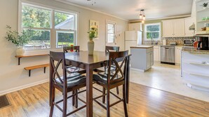 A kitchen with wooden flooring, white cabinets, a dining table with chairs, and a ceiling fan. - 16 Mi to WEC: Horse-Friendly Home on 5 Acres! (Williston)
