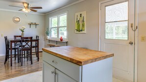 A kitchen with a wooden countertop, a dining table with chairs, a ceiling fan, and a window with a view of greenery. - 16 Mi to WEC: Horse-Friendly Home on 5 Acres! (Williston)