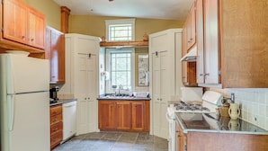 A kitchen with wooden cabinets, a refrigerator, a stove, and a window. - Romantic Pondside Escape: Country Cottage in Paris (Paris)