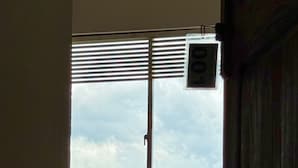 A room with a single bed, a window with blinds, and a view of a tree and mountains. - Vilona Inn (Nuwara Eliya)