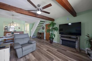 A living room with a sofa, a television, a fireplace, and a staircase.
