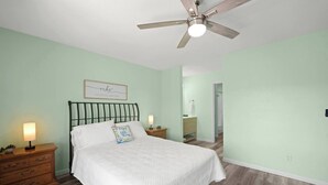 Una camera da letto con un letto, comodini, una ventola a soffitto e una lampada da notte.