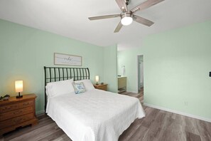 Ein Schlafzimmer mit Bett, Nachttischen, Deckenventilator und Nachttischlampe.