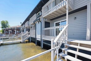 Ein Hotel direkt am Wasser mit mehreren Balkonen und einer anlegenden Mole.