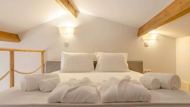 Un dormitorio con cama, dos luces empotradas en la pared y una viga de techo de madera.