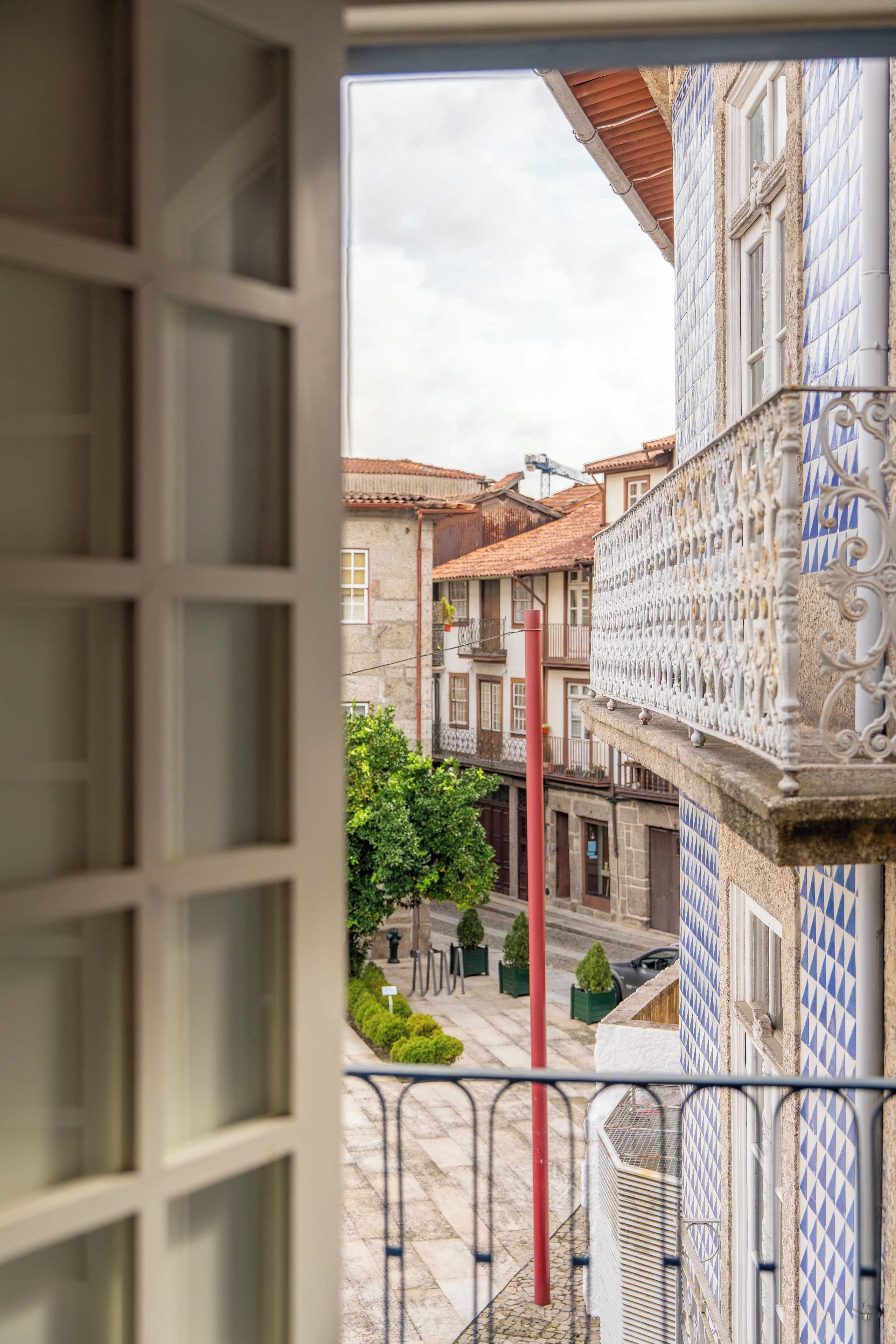 A balcony with a view of a traditional building with patterned tiles and a red pole.