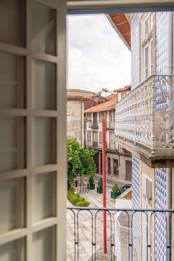 A balcony with a view of a traditional building with patterned tiles and a red pole.