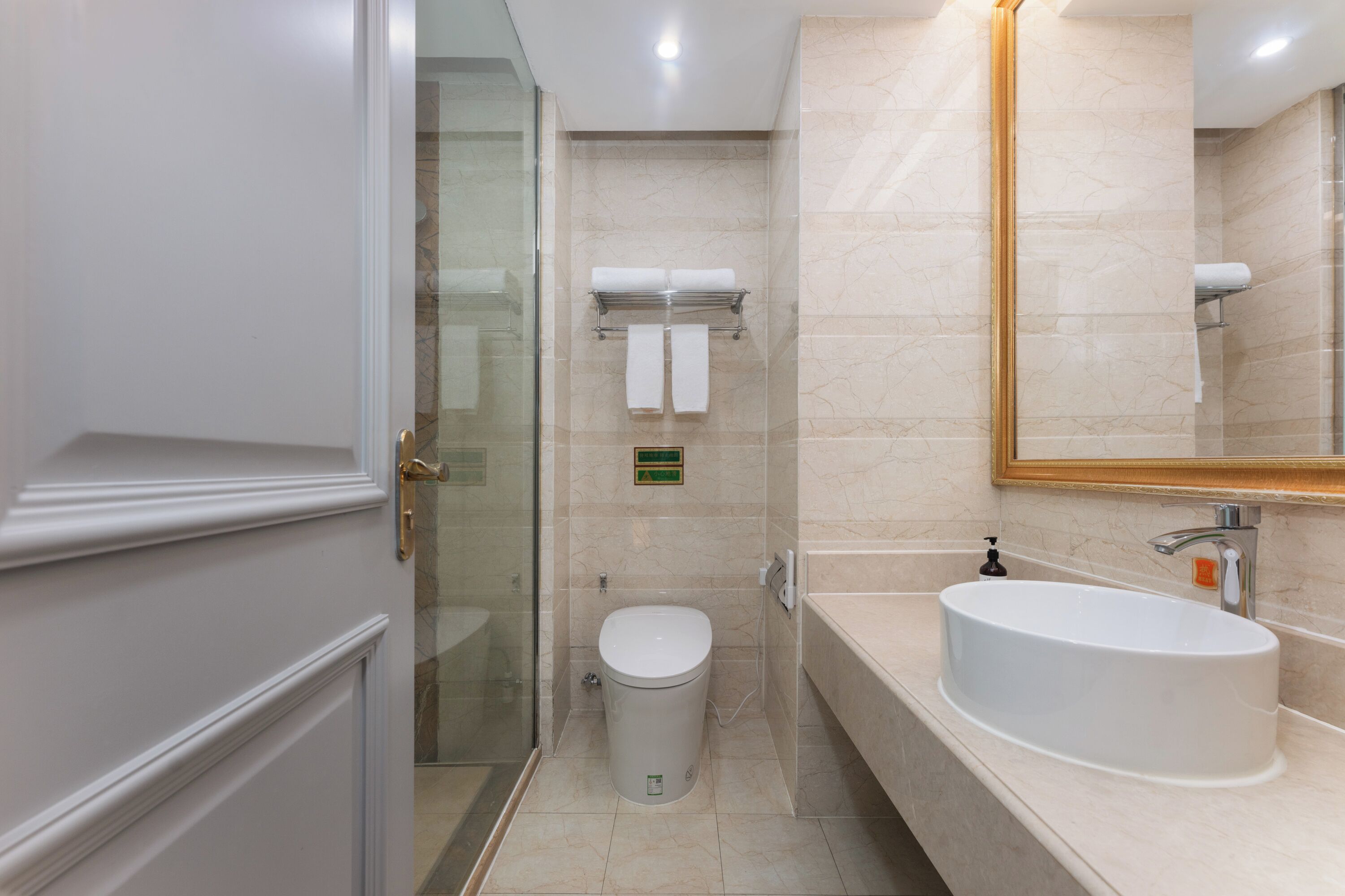 Une salle de bain moderne équipée de toilettes, d’un lavabo et d’une douche à parois de verre.