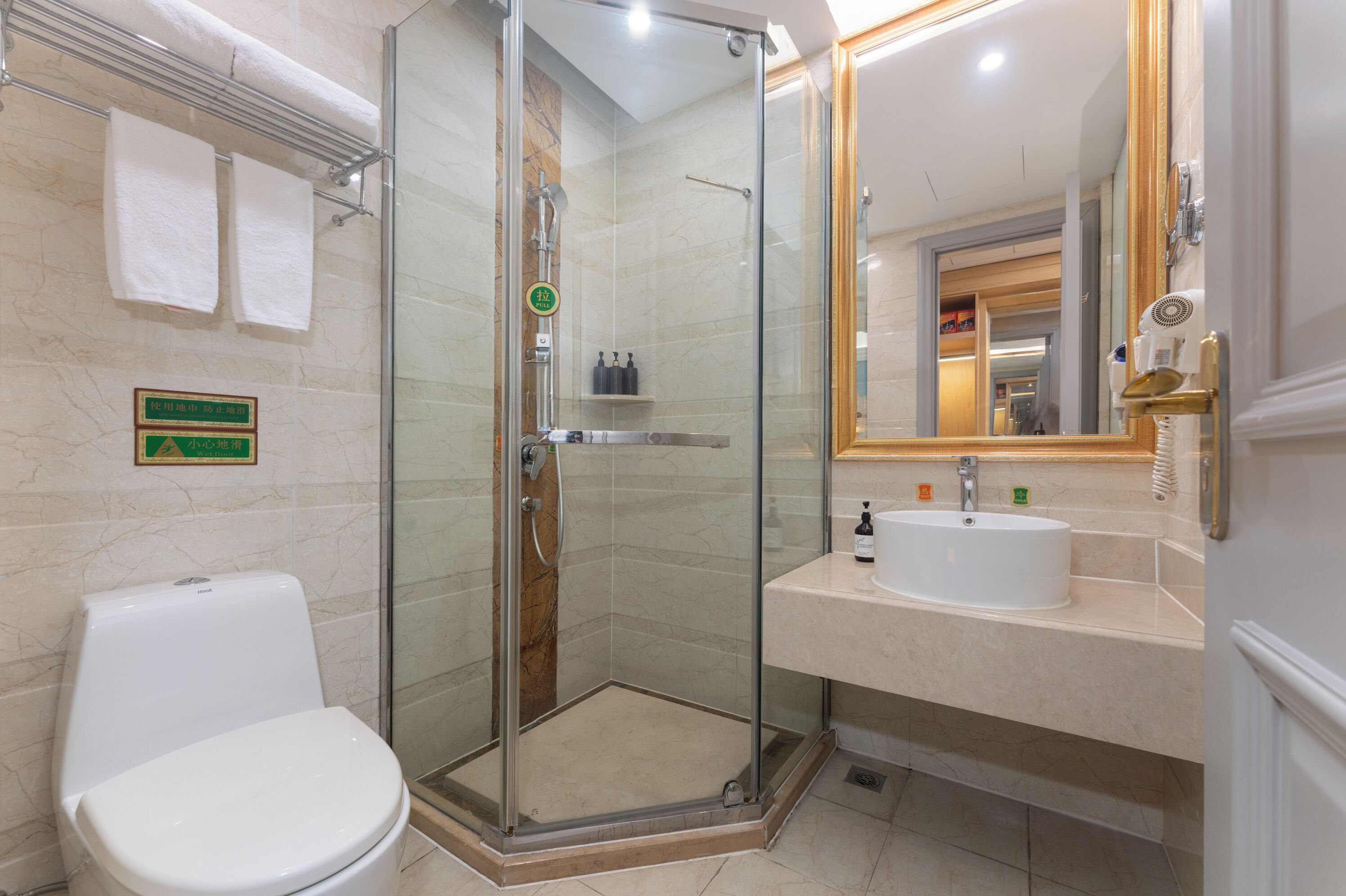 Une salle de bain moderne avec une douche à parois de verre, des toilettes blanches, un lavabo avec un miroir et un porte-serviettes.