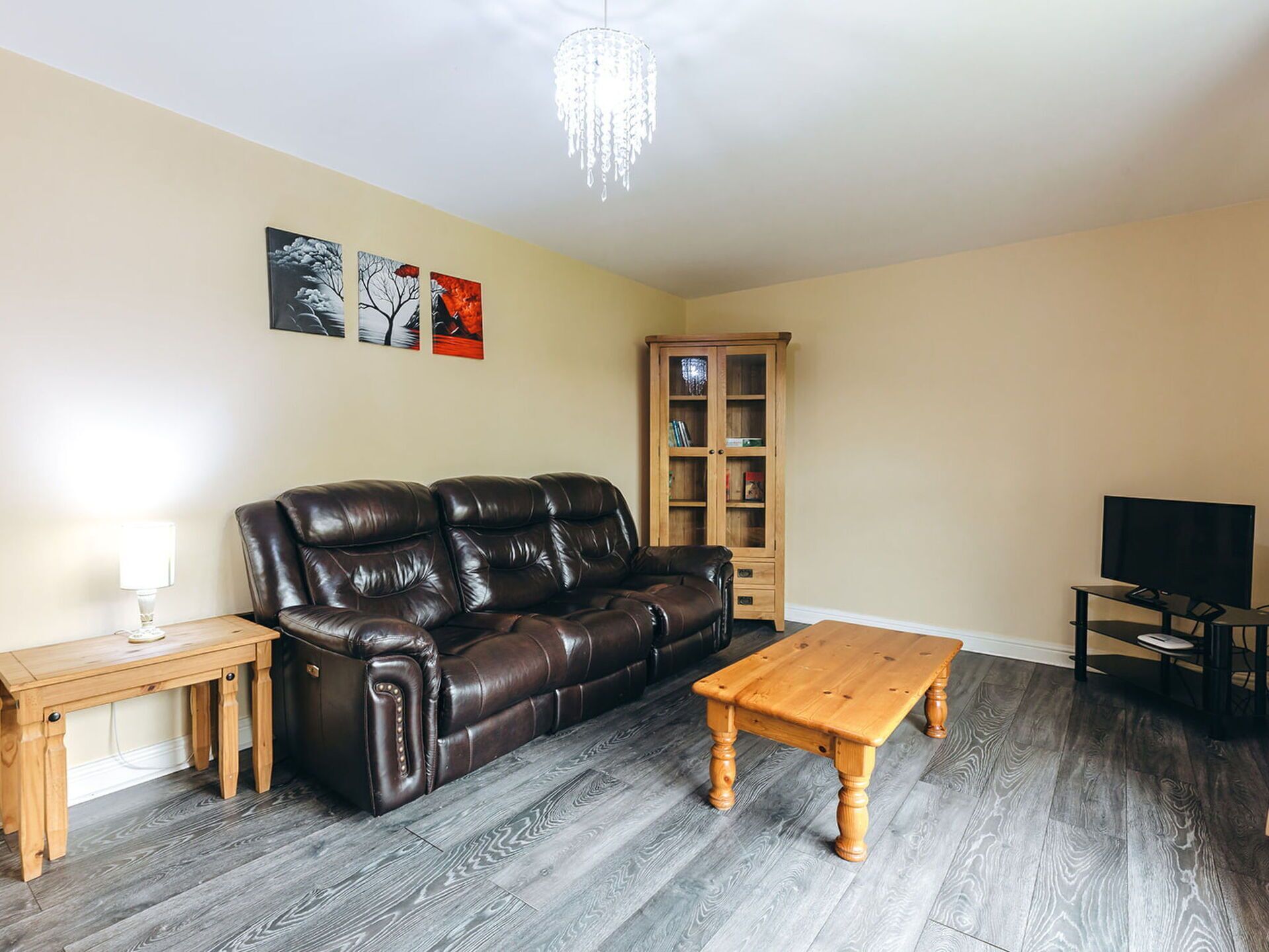 A living room with a leather sofa, wooden coffee table, and a cabinet.