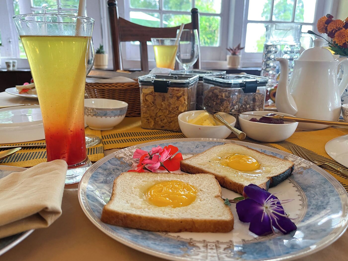 A breakfast setting with toast, a glass of juice, and various breakfast items on a table.