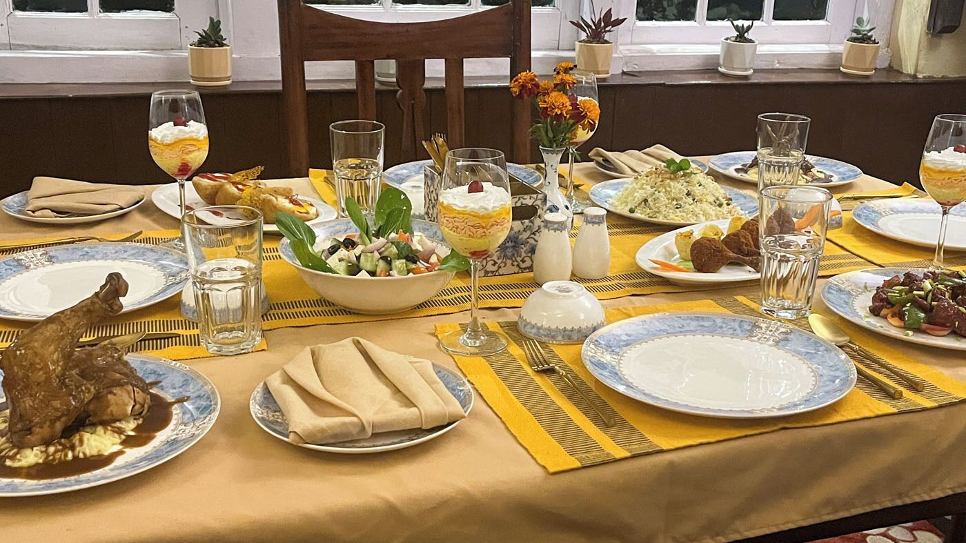 A dining table set with various dishes, glasses, and a vase of flowers.