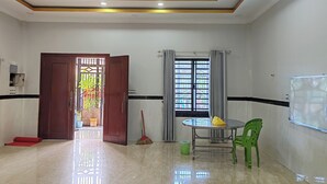A room with a tiled floor, a table with chairs, a window with curtains, and a door leading outside. - TCN Condo 168 (Phnom Penh)