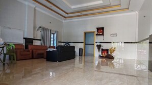 Uma sala de estar espaçosa com piso lustroso, sofá preto e um objeto decorativo na parede.