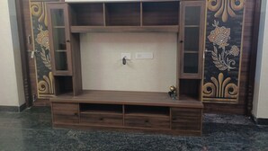 Een houten entertainmentkast met open vakken en een centraal kastje, omlijst door decoratieve panelen met bloemmotieven.