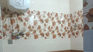 Een badkamer met een boiler, toilet en een groene kruk.