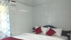 Een hotelkamer met een bed, een plafondventilator en een airconditioning.
