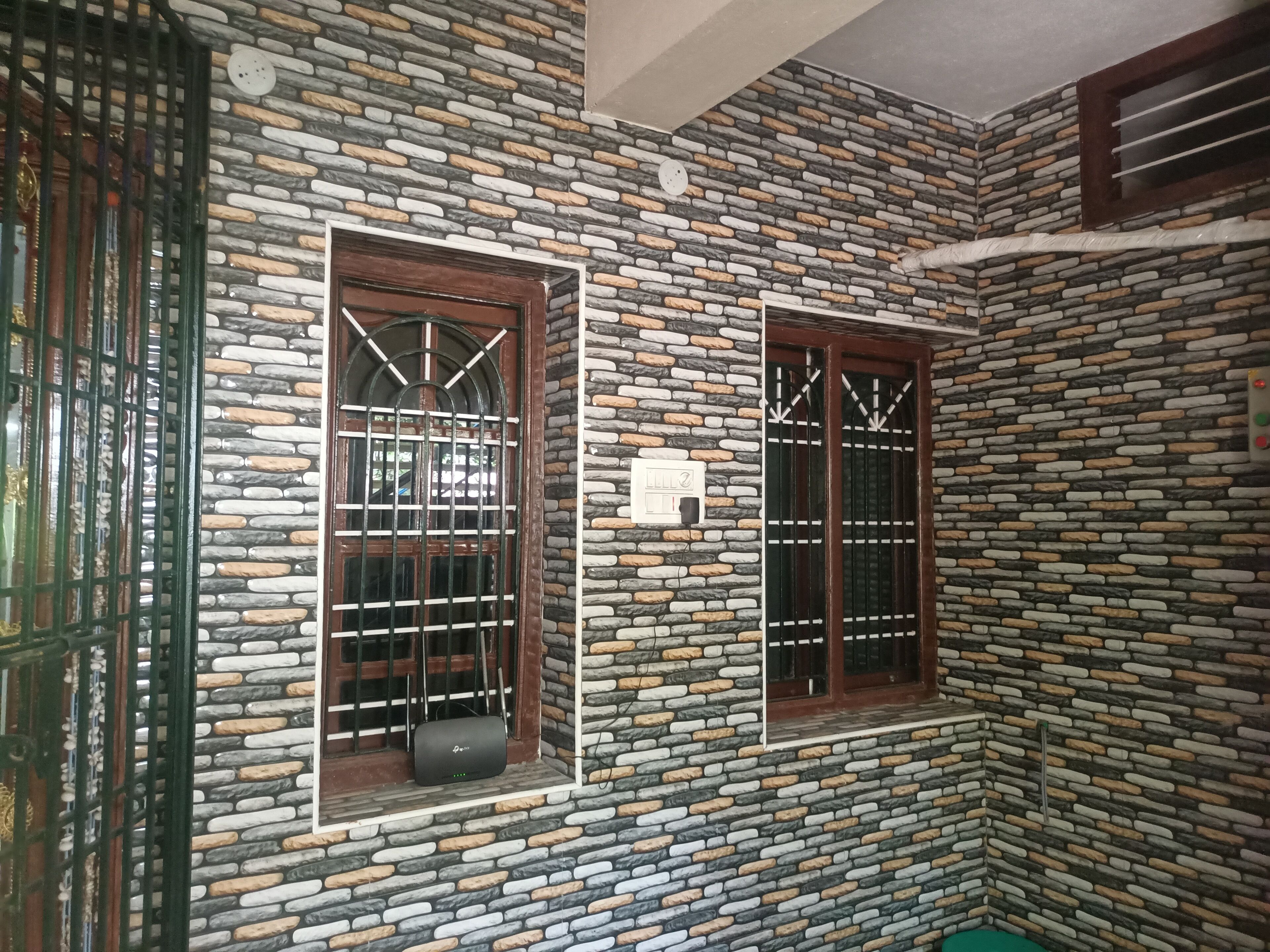 Una habitación con pared de piedra, dos ventanas con barrotes y un pequeño dispositivo en el alféizar.