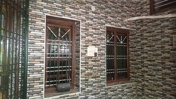 Una habitación con pared de piedra, dos ventanas con barrotes y un pequeño dispositivo en el alféizar.