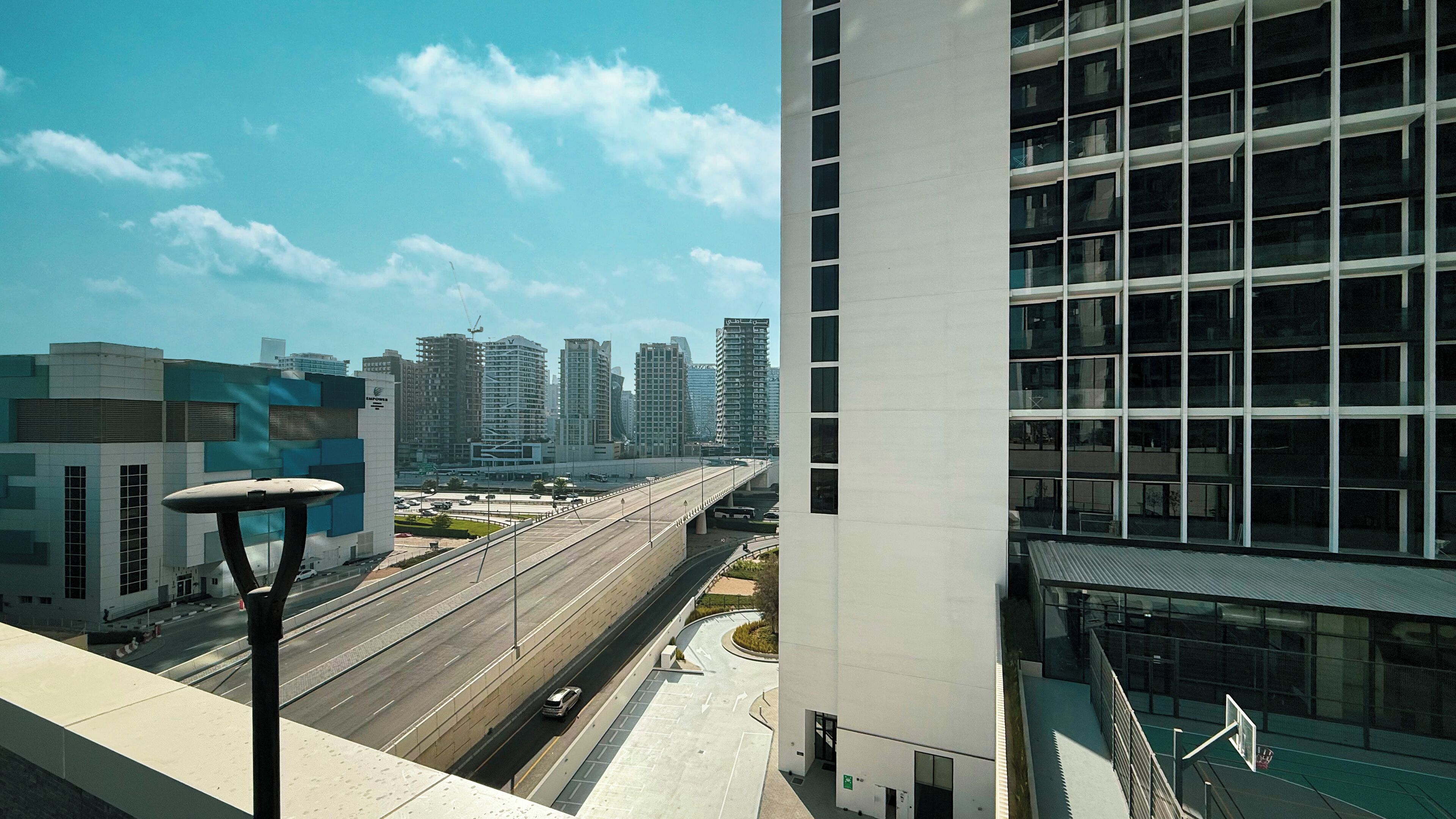 A modern building with a glass facade and a view of a cityscape with high-rise buildings.