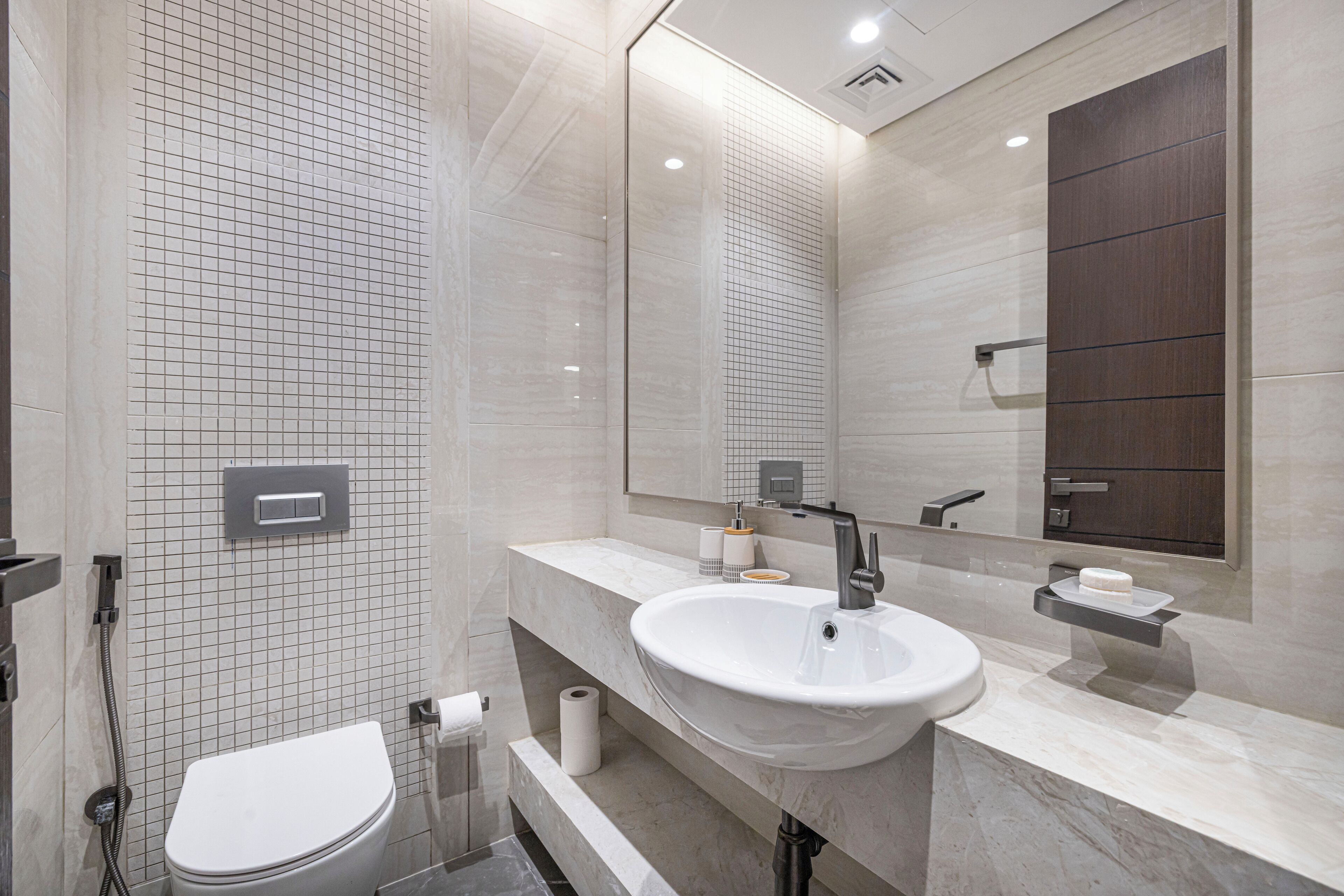 A modern bathroom with a white toilet, a sink with a mirror above it, and a shower area.