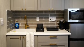 A kitchen with grey cabinets, a white countertop, a microwave, and a coffee maker.