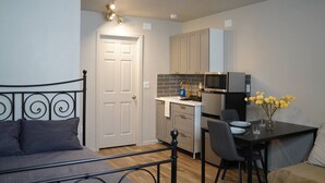 A compact living space with a bed, kitchenette, and dining area.