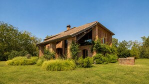 Una casa de ladrillo de un piso con techo de tejas, rodeada de un césped cuidado y diversos arbustos.