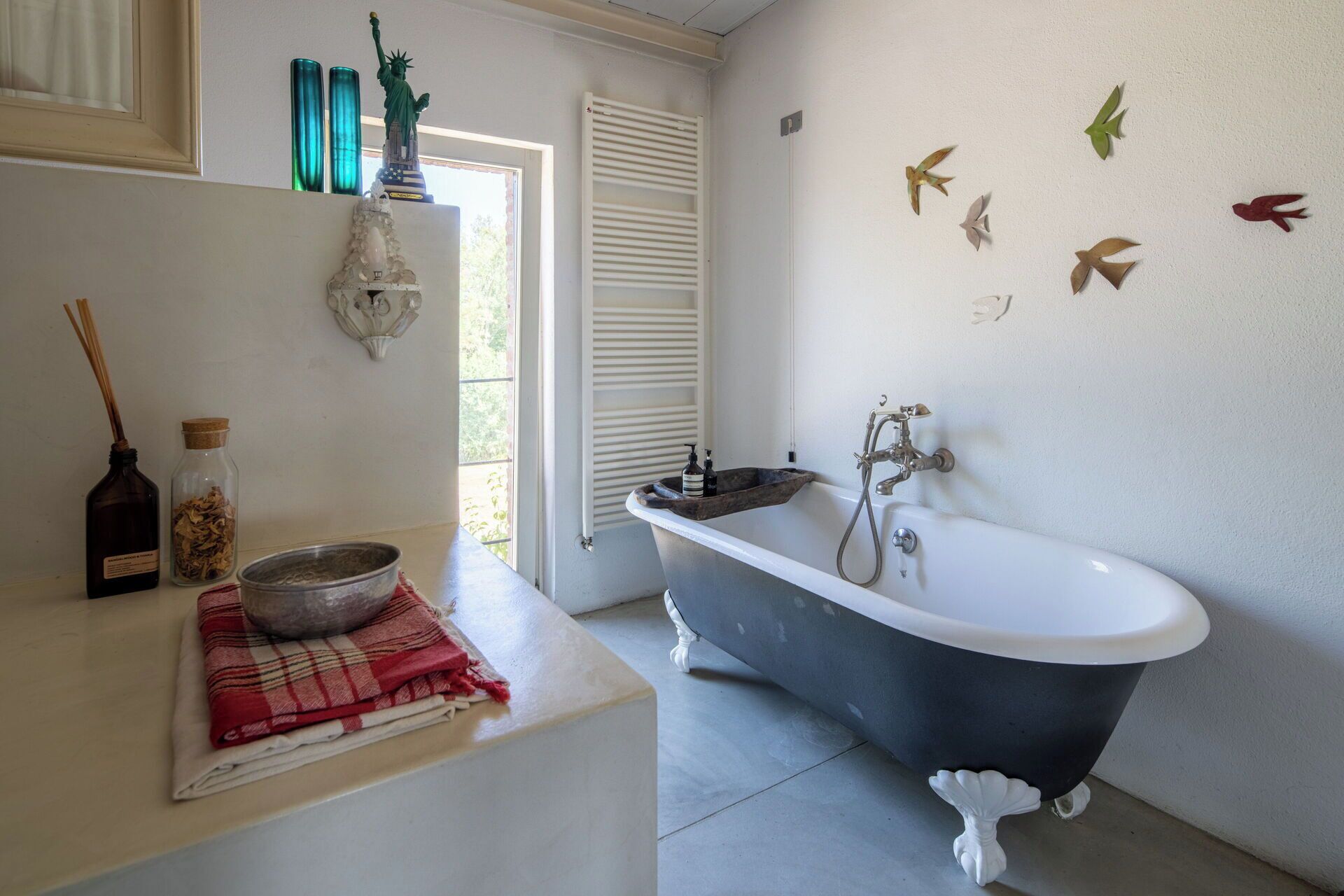 A bathroom with a freestanding bathtub, a sink, and decorative wall art.