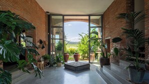 Un espacio interior amplio con vista a un paisaje verde a través de grandes puertas de vidrio.