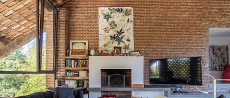 Una sala de estar con pared de ladrillo, chimenea, televisor de pantalla plana y estantería.