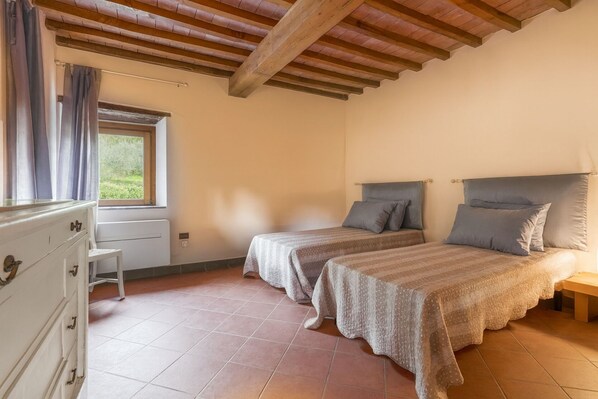 A bedroom with two beds, a dresser, and a window with curtains.