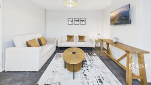 A modern living room with a white sofa, a round coffee table, and a wooden side table.