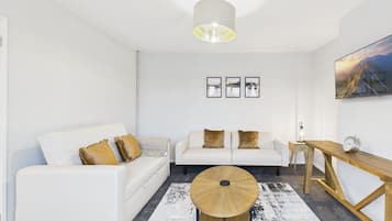 A modern living room with a white sofa, a round coffee table, and a wooden side table.