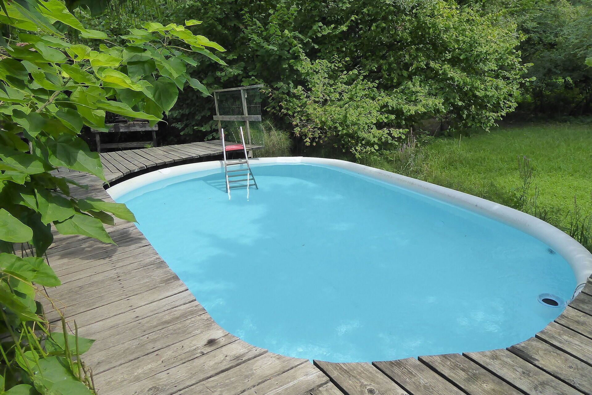 Une piscine rectangulaire entourée d’une terrasse en bois.