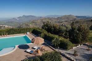 Piscina con sillas de descanso y vista a las montañas.