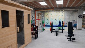 Une salle de sport avec un mur en bois, du matériel d’haltérophilie et un mur d’escalade.