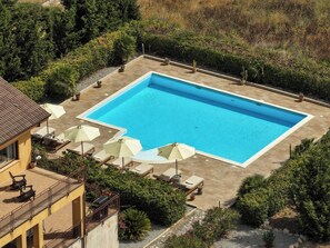 A rectangular swimming pool with a tiled deck surrounding it, equipped with several lounge chairs and umbrellas. - Sundrenched Sicilian Villa - Pool, Hot Tub, Gym, Sauna - Sleeps 10 Near Palermo (Ciminna Palermo)
