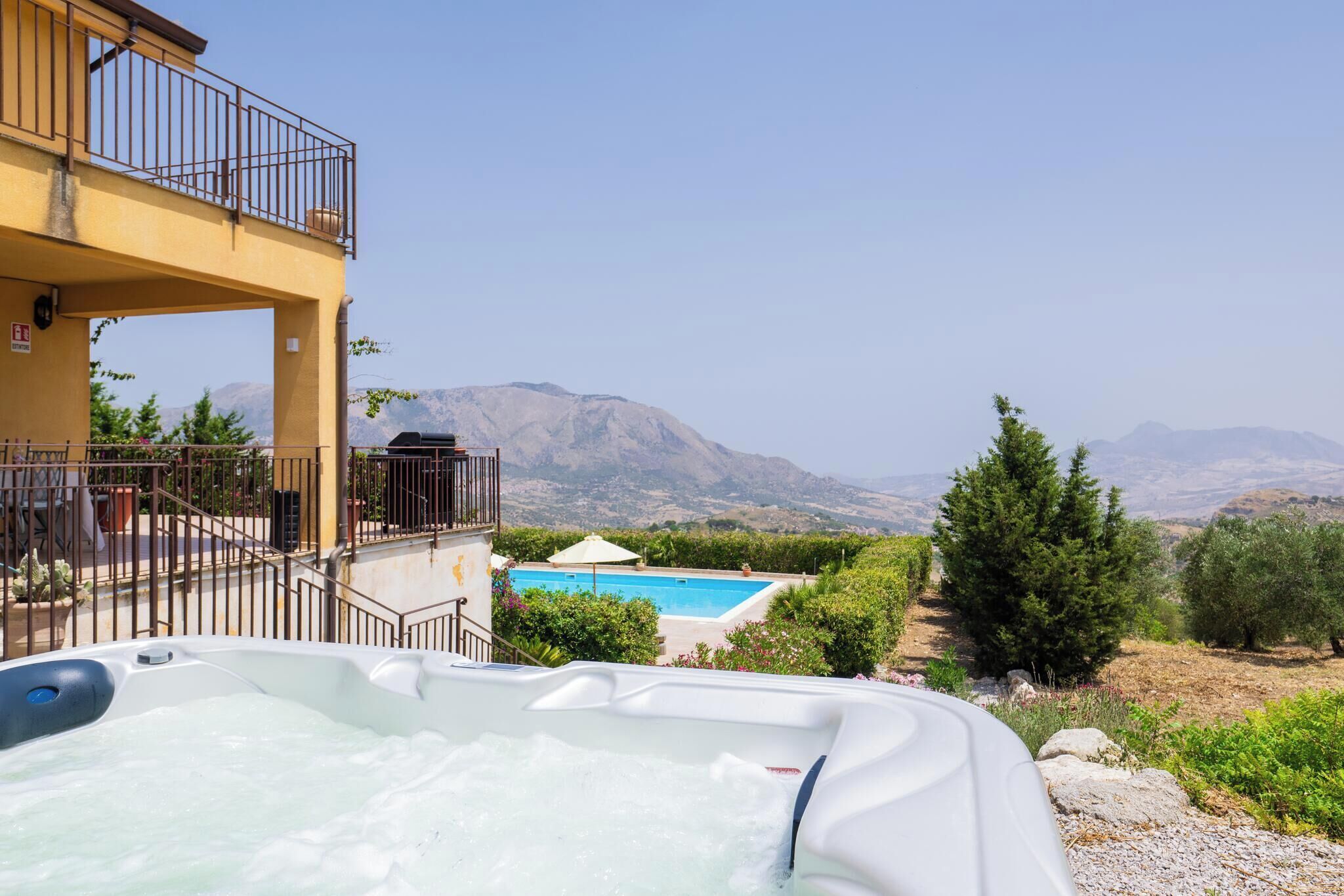 Un jacuzzi con vista a la montaña, una piscina y un balcón con barandilla.