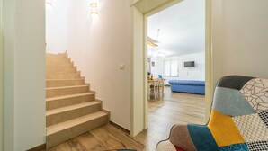 A staircase leading to a dining area with a blue couch and a television in the background. - VILLA GINEVRA: typical Salento pajara with swimming pool in the Salento countryside. (Montesano Salentino)