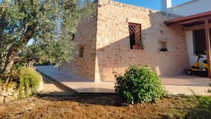 A stone building with a chimney, a small window, and a paved area with a bush. - VILLA GINEVRA: typical Salento pajara with swimming pool in the Salento countryside. (Montesano Salentino)